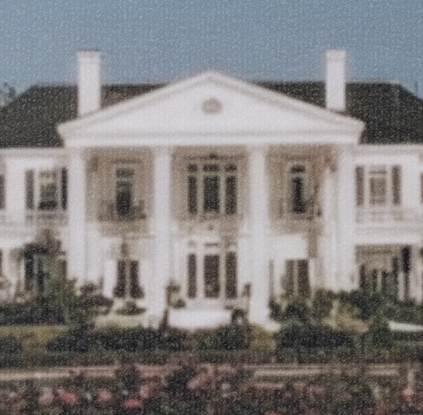A grand columned house with front gardens